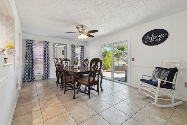 dining space featuring a ceiling fan, baseboards, a textured ceiling, and light tile patterned flooring