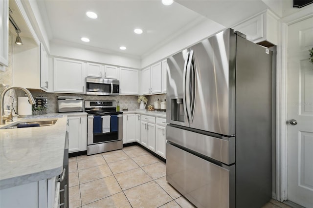 kitchen featuring a sink, decorative backsplash, light tile patterned floors, stainless steel appliances, and white cabinetry