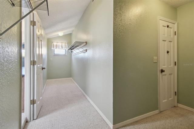 hallway featuring vaulted ceiling, baseboards, and carpet