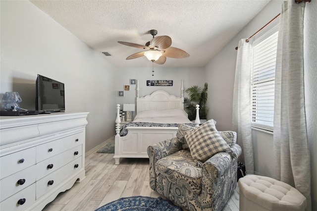 bedroom with a textured ceiling, multiple windows, visible vents, and light wood-style floors