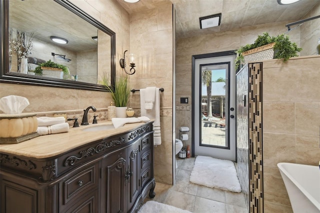 full bathroom with tile walls, a freestanding tub, and vanity