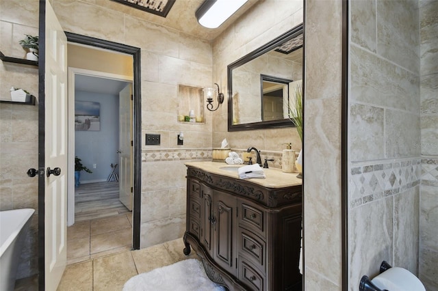 full bathroom featuring tile walls, a freestanding tub, tile patterned floors, and vanity