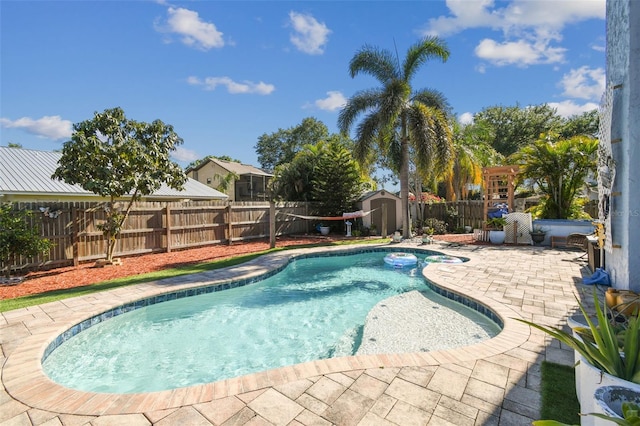 view of pool featuring a patio area, a storage shed, a fenced backyard, an outbuilding, and a fenced in pool