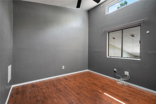 empty room featuring baseboards, a textured ceiling, wood finished floors, and a ceiling fan
