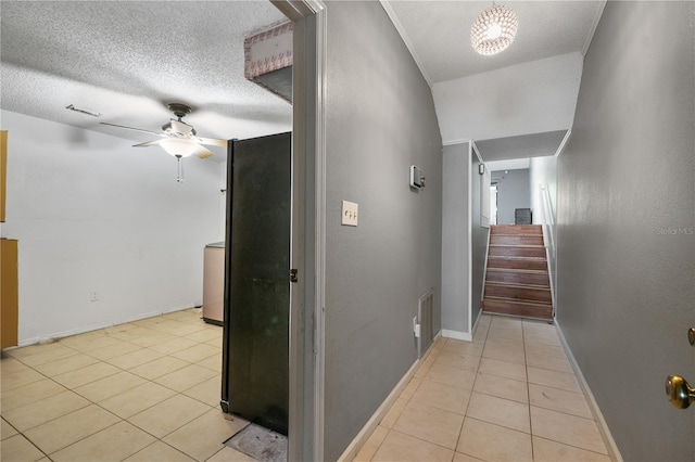 hall with light tile patterned flooring, a textured ceiling, baseboards, stairs, and washer / dryer