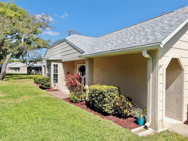 4851 Leyte Ct, New Port Richey, FL 34655 - view of side of home with a shingled roof, a lawn, and stucco siding