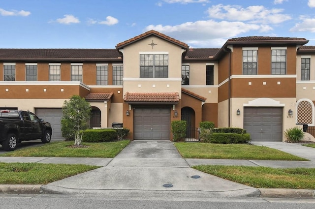 townhome / multi-family property with a tiled roof, driveway, stucco siding, and an attached garage