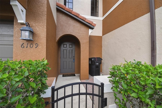 entrance to property with a gate, stucco siding, and a tiled roof