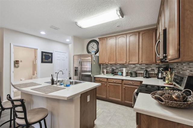 kitchen with a kitchen island with sink, a sink, backsplash, and appliances with stainless steel finishes