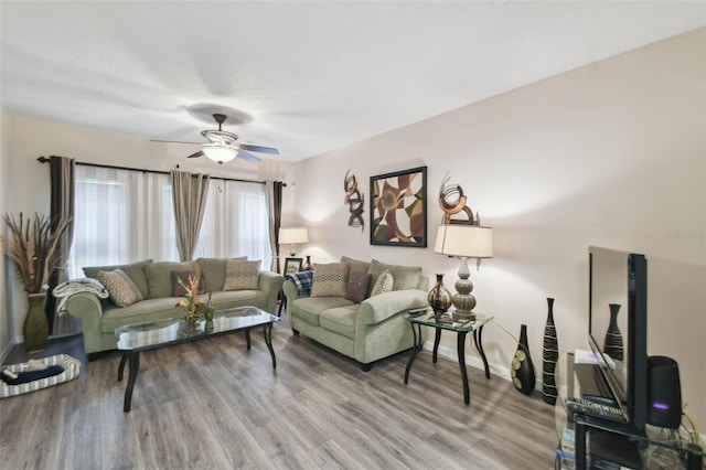 living area featuring baseboards, wood finished floors, and a ceiling fan