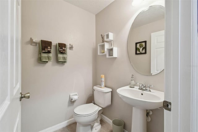 half bath with toilet, a sink, tile patterned floors, and baseboards