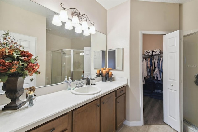 bathroom featuring a walk in closet, a stall shower, tile patterned flooring, and vanity