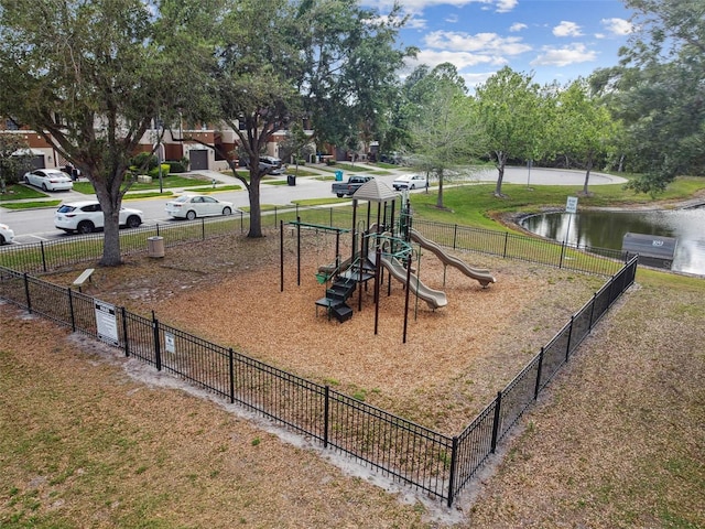 community playground featuring a lawn, a water view, and fence