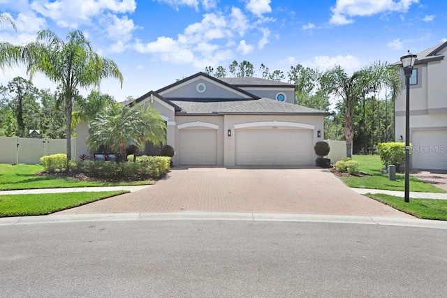 10703 Morning Dew Way, Tampa, FL 33647 - view of front of property featuring a front yard, stucco siding, fence, decorative driveway, and a garage