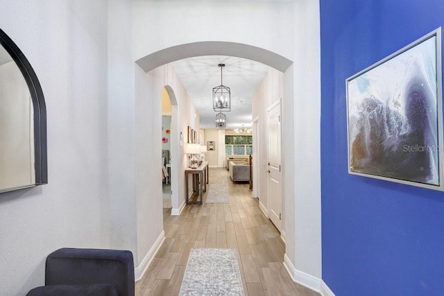 10703 Morning Dew Way, Tampa, FL 33647 - corridor with wood tiled floor, a notable chandelier, arched walkways, and baseboards