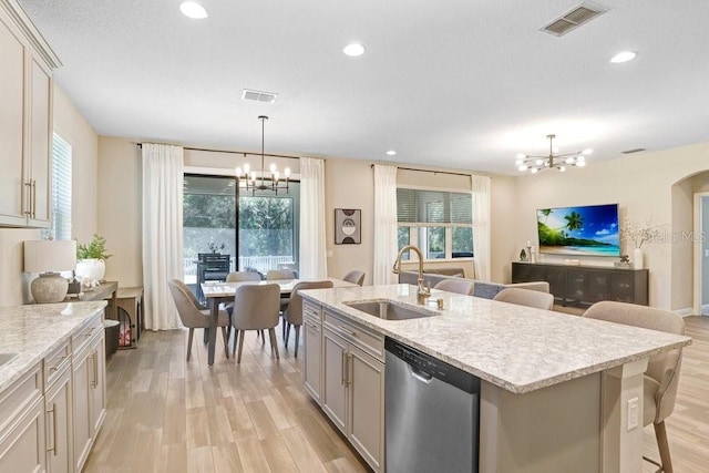 10703 Morning Dew Way, Tampa, FL 33647 - kitchen with visible vents, a sink, light wood-type flooring, stainless steel dishwasher, and a notable chandelier