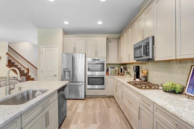 10703 Morning Dew Way, Tampa, FL 33647 - kitchen with tasteful backsplash, a sink, light wood-style floors, light stone counters, and appliances with stainless steel finishes