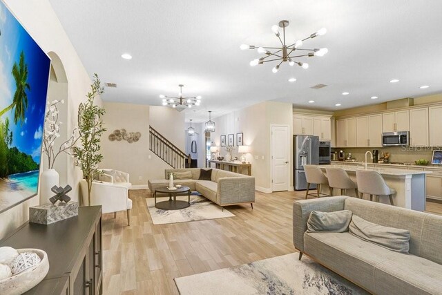 10703 Morning Dew Way, Tampa, FL 33647 - living room featuring recessed lighting, a notable chandelier, stairway, and light wood-type flooring