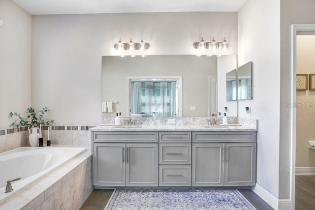 10703 Morning Dew Way, Tampa, FL 33647 - full bathroom featuring baseboards, a sink, a garden tub, double vanity, and wood finished floors