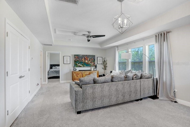 10703 Morning Dew Way, Tampa, FL 33647 - living room with light colored carpet, baseboards, a textured ceiling, a raised ceiling, and a notable chandelier