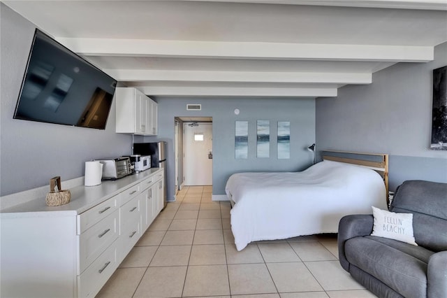 bedroom featuring light tile patterned floors, visible vents, freestanding refrigerator, and beam ceiling