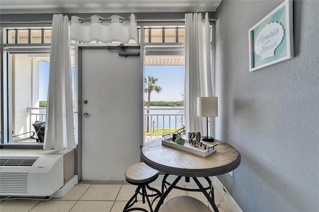 interior space featuring light tile patterned floors, a textured wall, an AC wall unit, and a water view