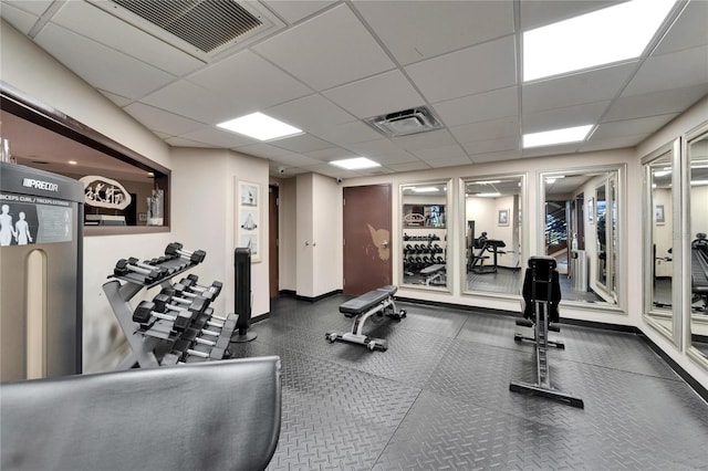 exercise room featuring a paneled ceiling, baseboards, and visible vents