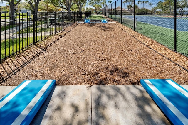 view of home's community featuring a tennis court and fence