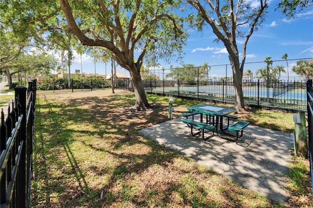 view of community featuring a water view, a yard, and fence