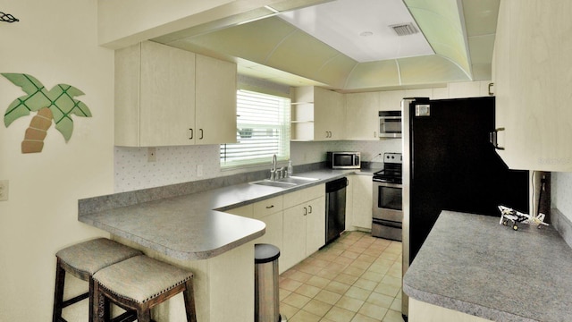 6035 19th St NE, Saint Petersburg, FL 33703 - kitchen with a sink, appliances with stainless steel finishes, a peninsula, a breakfast bar area, and open shelves