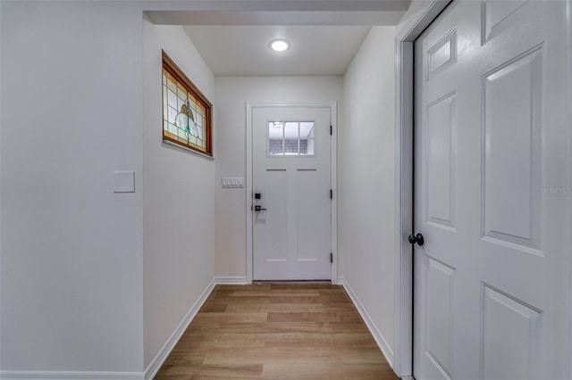 doorway to outside with light wood finished floors and baseboards