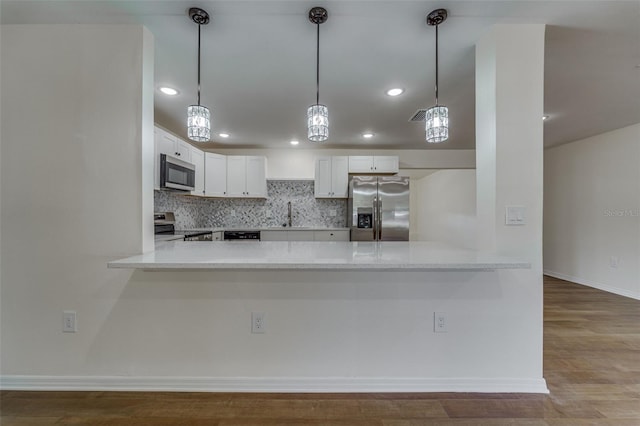 kitchen with light countertops, stainless steel appliances, backsplash, and a peninsula