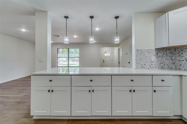 kitchen featuring white cabinetry, light countertops, hanging light fixtures, and tasteful backsplash
