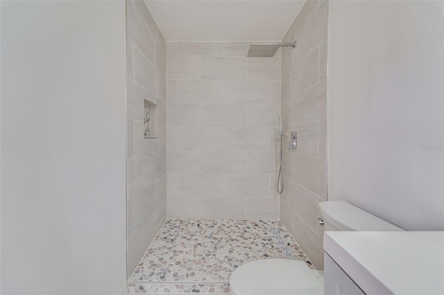 full bath with toilet, a tile shower, and vanity