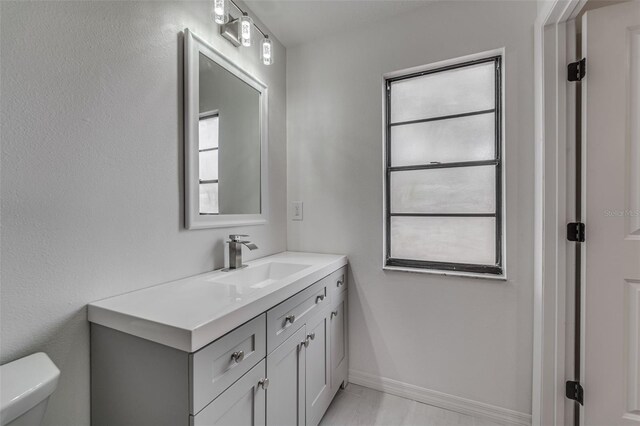 bathroom featuring toilet, vanity, and baseboards