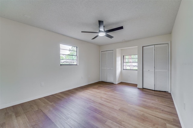 unfurnished bedroom featuring multiple closets, multiple windows, and light wood-type flooring