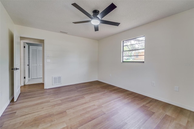 unfurnished room featuring ceiling fan, a textured ceiling, light wood finished floors, and visible vents