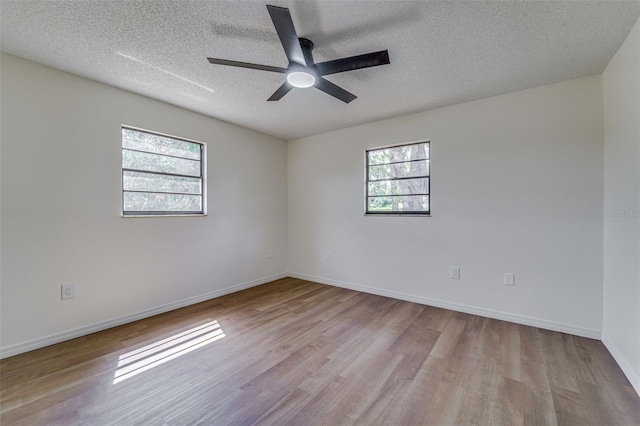empty room featuring a ceiling fan, a textured ceiling, baseboards, and wood finished floors