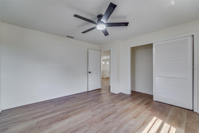 unfurnished bedroom with a closet, a textured ceiling, visible vents, baseboards, and light wood-type flooring