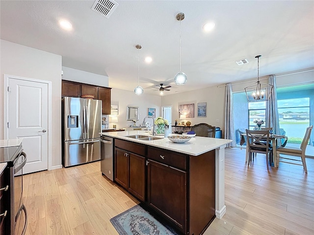 20983 Monza Loop, Land O Lakes, FL 34638 - kitchen featuring stainless steel appliances, a sink, dark brown cabinetry, light wood finished floors, and light countertops
