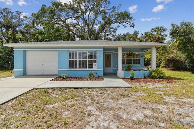 view of front of property featuring a porch, an attached garage, driveway, and stucco siding