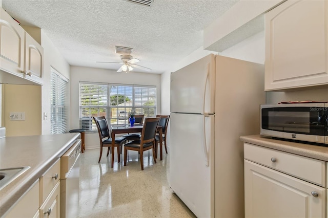 kitchen featuring a ceiling fan, a textured ceiling, white appliances, and light speckled floor