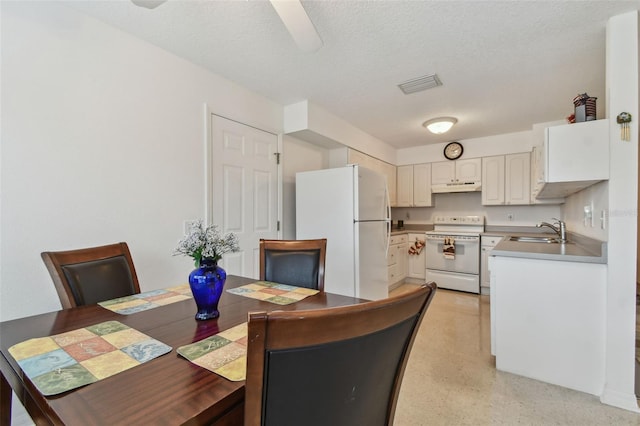 dining area featuring a ceiling fan, visible vents, light speckled floor, and a textured ceiling