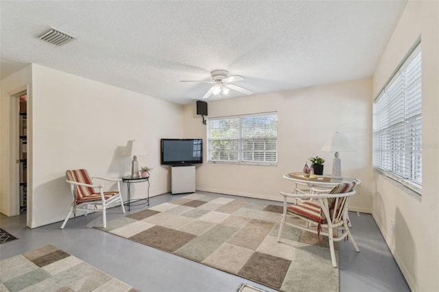 interior space featuring visible vents, baseboards, a ceiling fan, a textured ceiling, and finished concrete floors