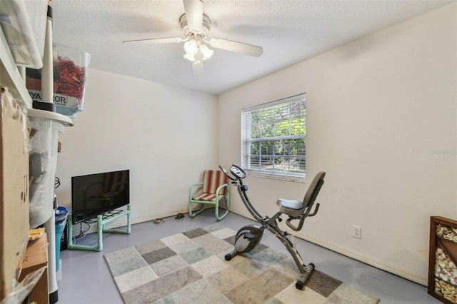 exercise area featuring a textured ceiling, baseboards, and a ceiling fan