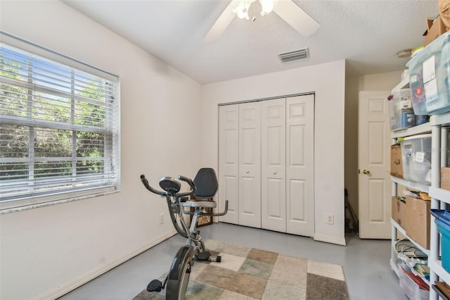 exercise area with a textured ceiling, baseboards, a ceiling fan, and visible vents