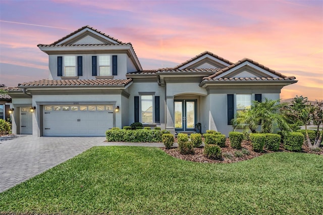 mediterranean / spanish house with french doors, a tile roof, stucco siding, and a lawn