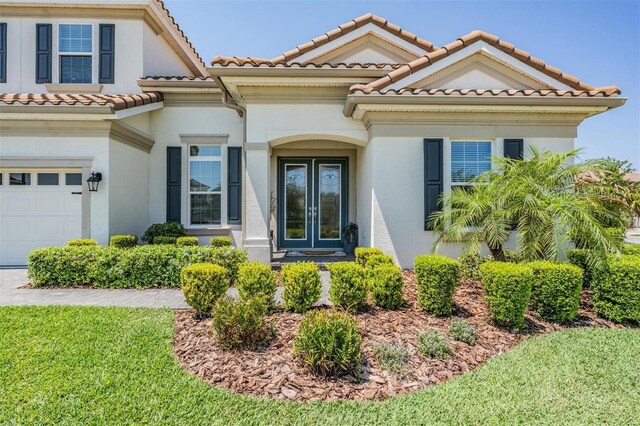 mediterranean / spanish-style house with stucco siding, an attached garage, a tiled roof, and a front yard