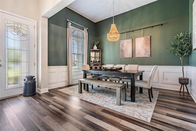 dining space with a notable chandelier, a wealth of natural light, dark wood-type flooring, and a decorative wall