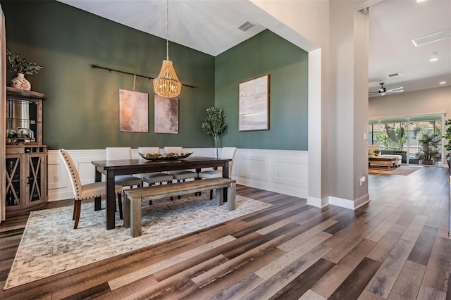 dining area with dark wood finished floors, a wainscoted wall, visible vents, and ceiling fan with notable chandelier